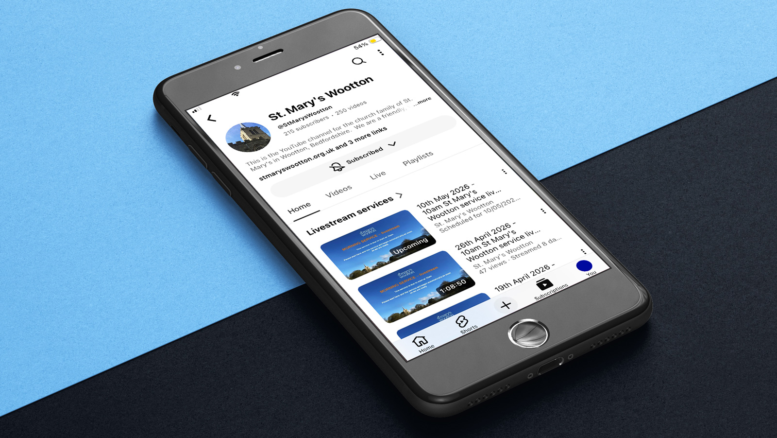 An iphone on a blue and blackground, showing the St Mary's YouTube channel page.
