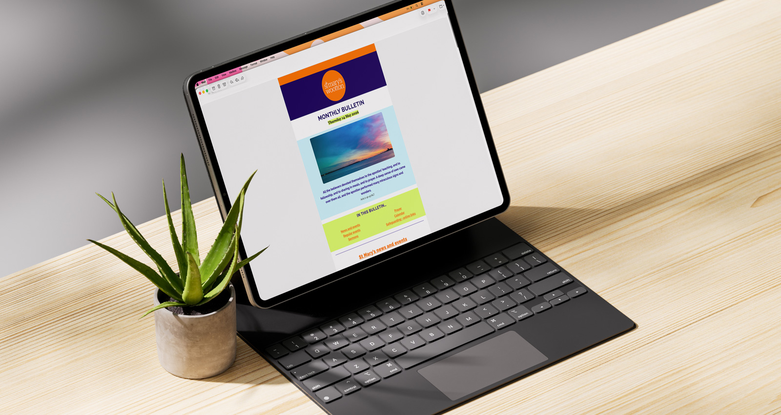 A tablet computer on a folio stand, showing the St Mary's email bulletin, on a wooden desk next to a potted plant.