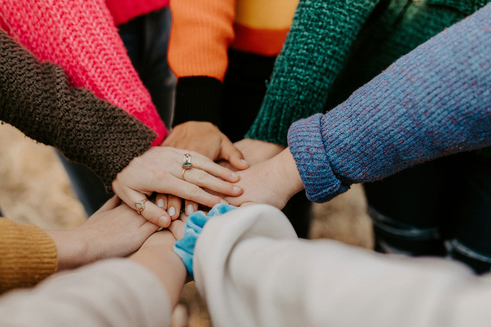 Colourful sleeves in a circle with their hands together.
